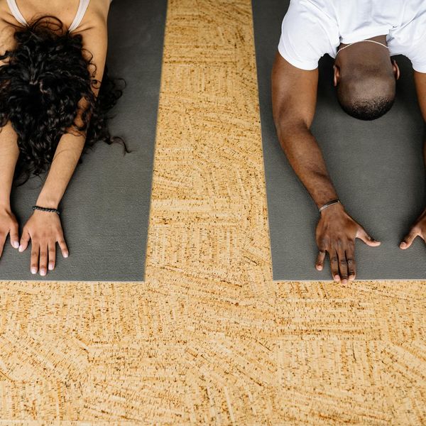 Man stretching on a yoga mat with a serene expression indoors.